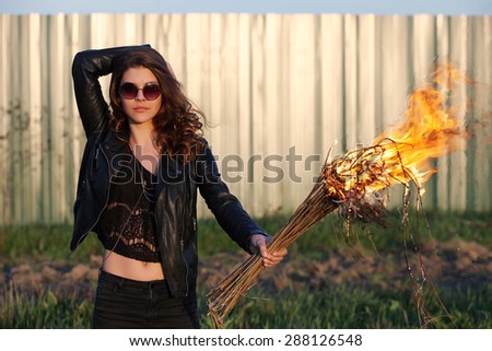 The bad woman in sunglasses and a black jacket holding a torch