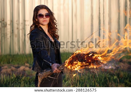 The bad woman in sunglasses and a black jacket holding a torch