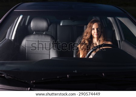 Sexy girl sit behind the wheel of the car and makes faces