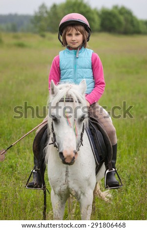 Little girl in the clothes for riding a horse sitting Sharpness on the girl  Outdoors