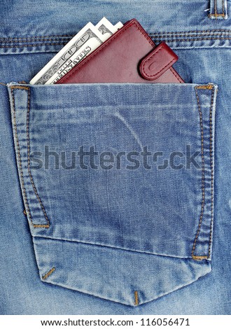 money dollars and brown leather wallet in jeans back pocket blue color background