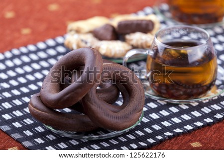 plate with pretzel next to two cups of tea studio shot