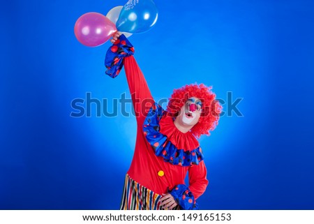 Happy clown with balloon on blue background studio inside shot