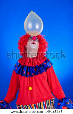 Happy clown with balloon on blue background studio inside shot