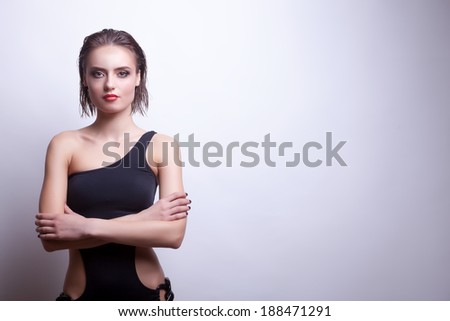 Sexy woman in black swimsuit on grey background. Studio shooting