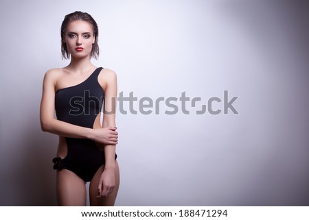 Sexy woman in black swimsuit on grey background. Studio shooting