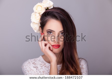 Beautiful woman flowers in head on grey background. Professional make up and hairstyle. Studio lighting