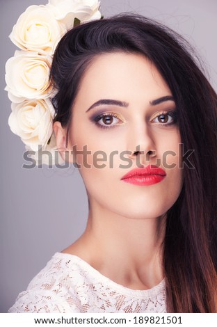Beautiful woman flowers in head on grey background. Professional make up and hairstyle. Studio lighting