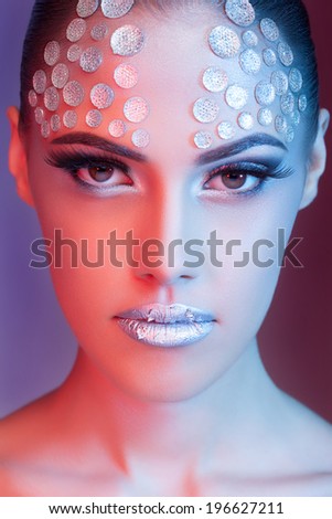 Sensual woman with fashion rhinestone make up. Blue and red colors on background. High end retouching. Clean skin with texture