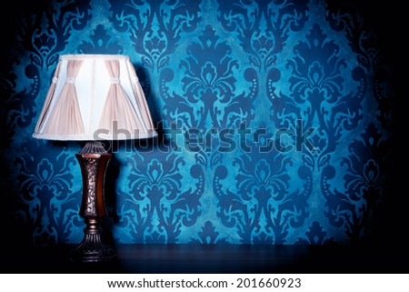 Vintage lamp on blue rococo pattern background. Victorian. Retro. Illumination. Wooden lamp on pattern background