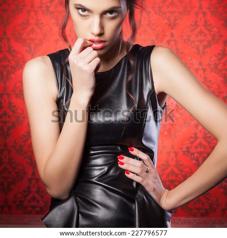 Sexy woman in leather jacket bitting her lips. Vintage red room. Rich interior