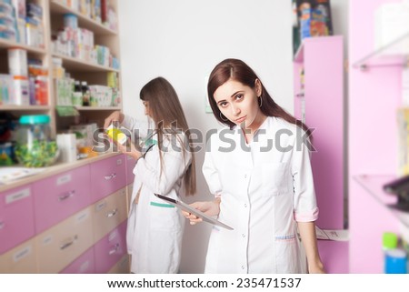 Nurse with digital tablet in hands inside pharmacy. Health care system. The second one is verifying a product in back