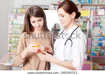 Pharmacist showing product to client inside a pharmacy. Indoor pharmacy shooting