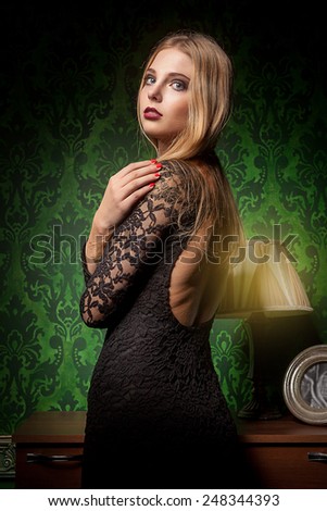 Sensual woman in black dress on green vintage interior. Retro styled. Old fashioned lady. Beauty and sensuality