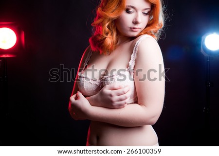 Sexy overweight woman in studio on black background with two light behind her. Chubby but sexy woman