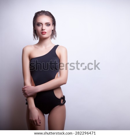 Sexy woman in swimsuit on grey background. Professional make up and hairstyle. Studio shooting