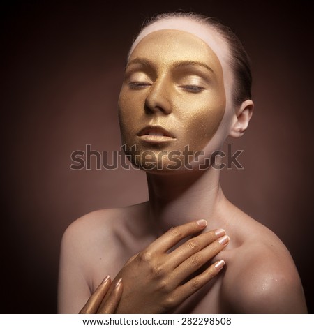 Beautiful woman with art fashion make up. Cosmetics and art fashion. Gold tone. Studio lighting. Face painting
