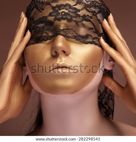 Woman with a gold fashion face and lace on her eyes. Professional make up. Sensuality. Gold oil. Mouth