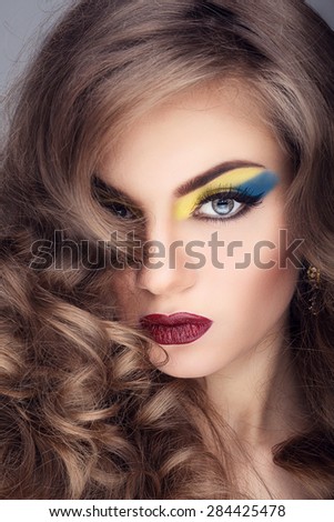 Beautiful girl with artistic make up on grey background. Studio shooting. Beauty and fashion make up in studio. Healthy skin and hair