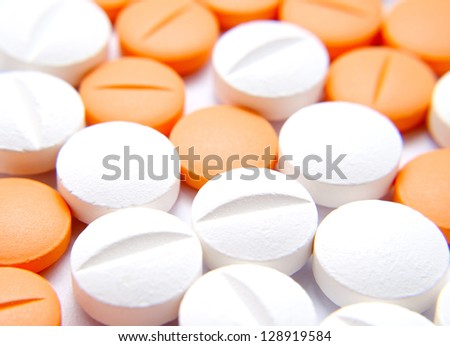 White and orange pills over white paper