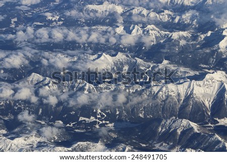 Alps, Austria. January 18, 2015. Flying over the Alps in Austria. You can see also ski a ski center among the mountains.