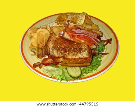 Ham and cheese sandwich toasted lettuce potato chips pickle yellow background