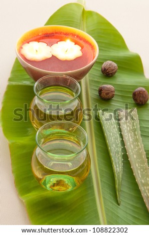 Health spa, two bottles of essential oil with of fresh aloe vera and candle on banana leaf.