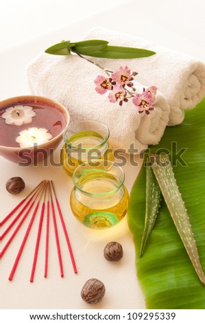 Health spa, two bottles of essential oil with of fresh aloe vera, towels, candle, incense, one with orchid flowers.
