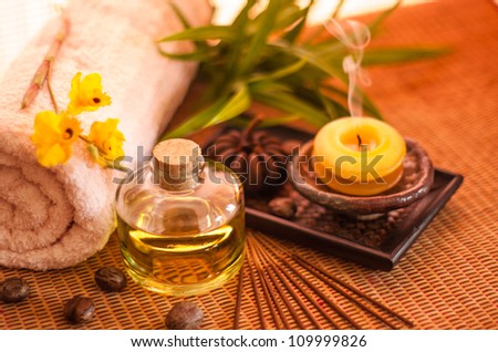Essential oil bottles, towels, candle and flower in health spa for spa treatment. [Focus at the oil bottle]