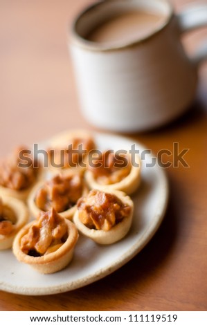 Cashew tart on serving plate with cup of coffee . [Focus with a cashew tart]