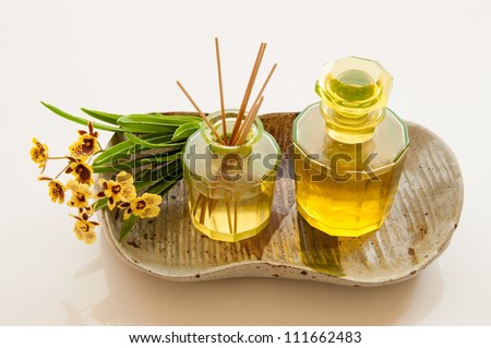 Aromatic essence oil bottle with bottle of fragrance reeds diffuser and bunch orchid flower.