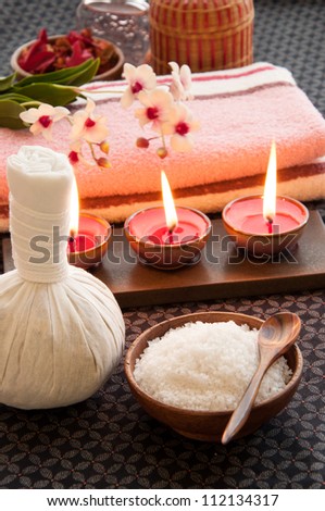 Spa still life with exfoliation salt scrub, herbal massage ball and spa accessories.