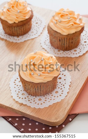 Cupcakes dessert with butter-cream swirl topping and sugar pearls decoration.