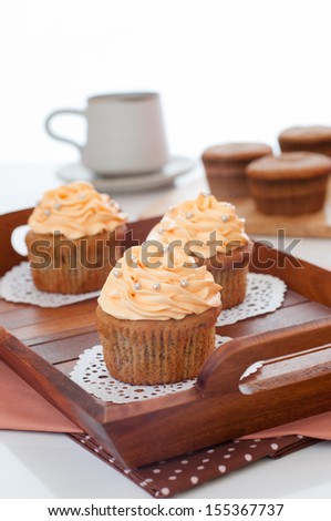 Cupcakes dessert with butter-cream swirl topping and sugar pearls decoration for coffee and tea.