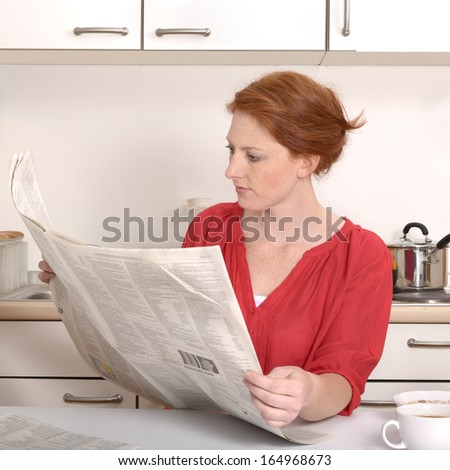 Pretty red haired woman reading newspaper, Studio Shot
