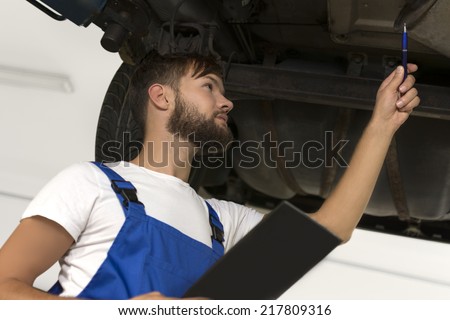 Male car mechanic working under car, Studio Shot