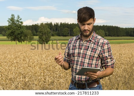 Young farmer with tablet inspecting crop, Outdoor Shot