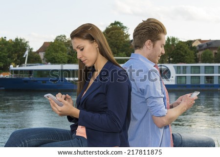 Young couple tapping text messages , Outdoor Shot