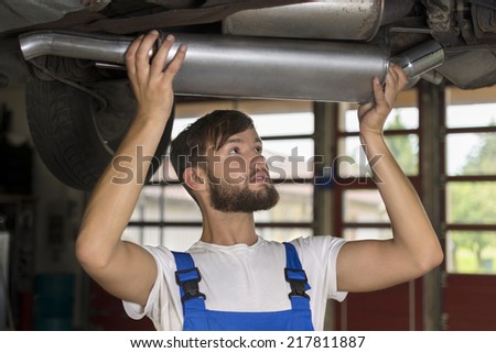 Male car mechanic changing car exhaust, Studio Shot