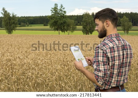 Young farmer with tablet inspecting crop, Outdoor Shot