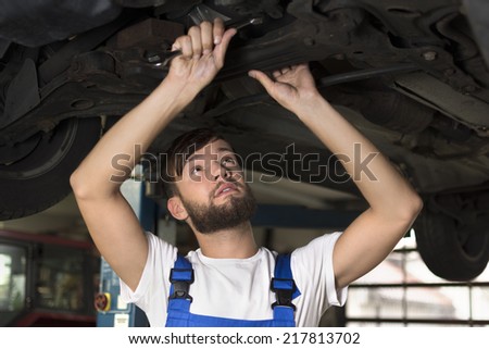 Male car mechanic working under car, Studio Shot