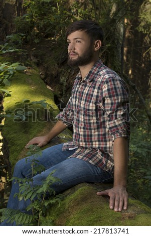 Young adventurer sitting on a trunk enjoying nature, Outdoor Shot