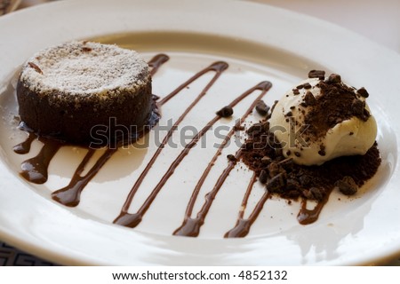 A decadent chocolate cake infused with liquid chocolate, and vanilla ice cream on the side.