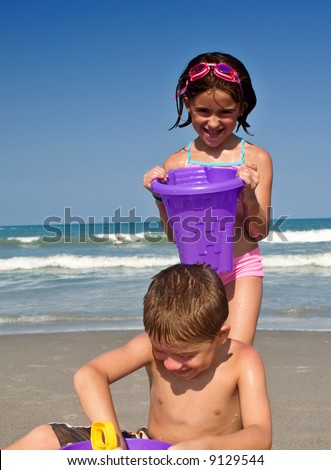 Sister sneaks up on brother and dumps a bucket of water on his head. Coco Beach Florida.