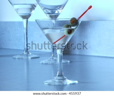 A vodka martini in a mini glass stands before two regular martini glasses.