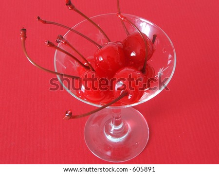 Red maraschino cherries in a martini glass.