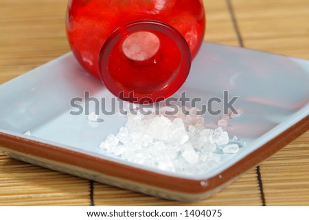 Bath salts spill from a bright red jar.