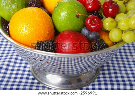 Freshly washed fruits drain in a stainless steel colander.