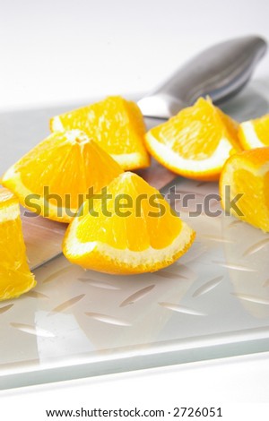 High-key shot of oranges on a cutting board with chef\'s knife.