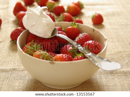 A dollop of fresh whipped cream rests on a bowl of strawberries.